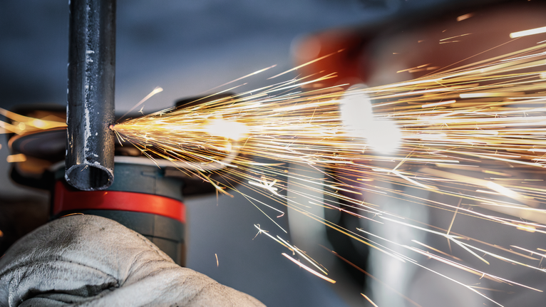 配戴安全設備的人員研磨金屬管，產生明亮的火花。