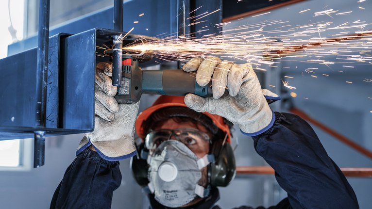 配戴安全設備的人研磨金屬，產生火花。