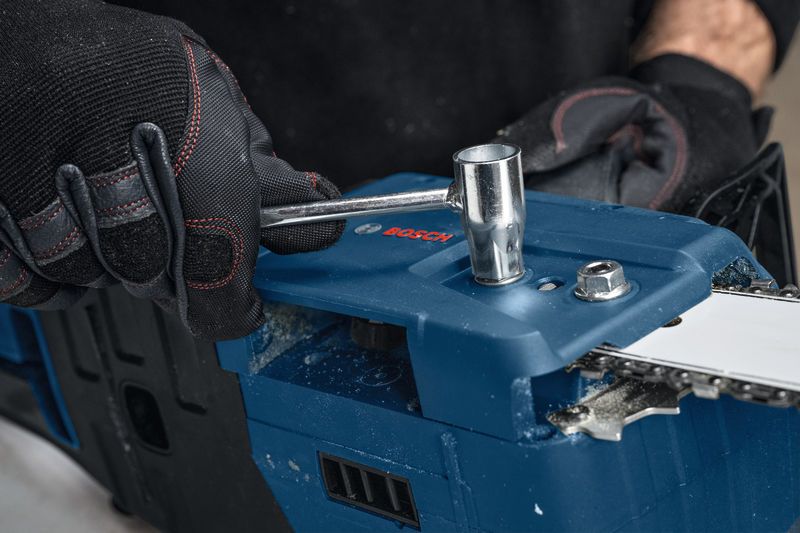 GKE 18V-40 一名配戴安全設備的人正在用扳手調整無線電鋸。.