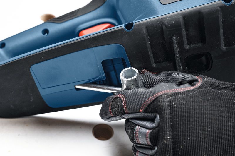 一名配戴安全設備的人使用扳手調整無線電鋸。.