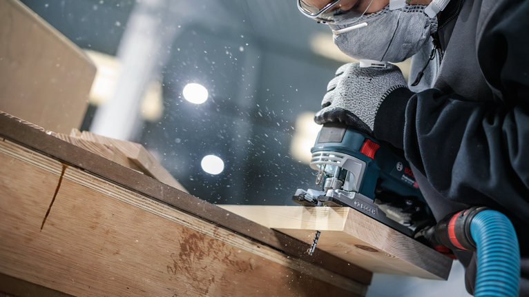 PRO Wood precise T144DP 線鋸片,100 mm,5 片 一名佩戴安全設備的人正在使用曲線鋸切割木材。