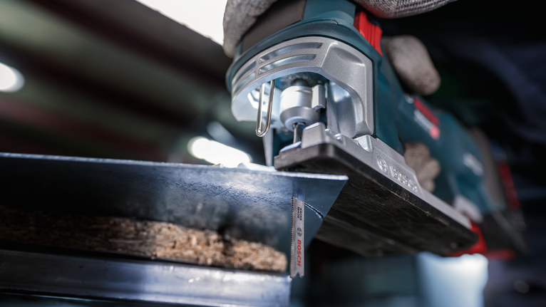 配戴安全設備的人員用曲線鋸切割木材。