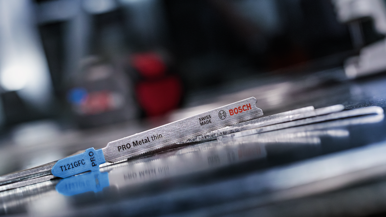 金屬拼圖刀片位於車間內反光的金屬表面上。