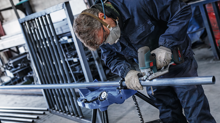 一名配戴安全設備的人員在工業車間內打磨金屬管路。