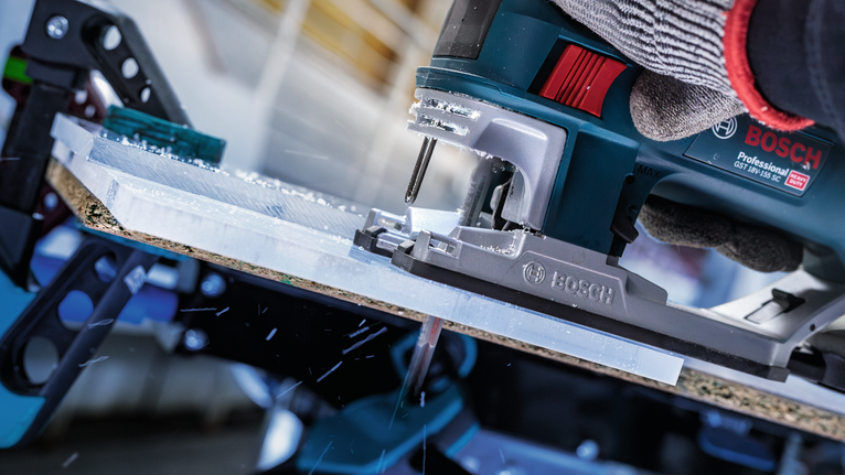 配戴安全設備的人員用曲線鋸切割塑膠片。