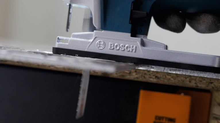 配戴安全裝備的人員引導拼圖鋸切割木板。