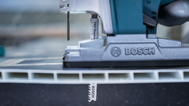PRO Plastics PVC 細緻切割款 T102H 線鋸片,100 mm,2 件 在工作坊的特寫場景中,拼圖鋸切開了一塊厚塑膠板。
