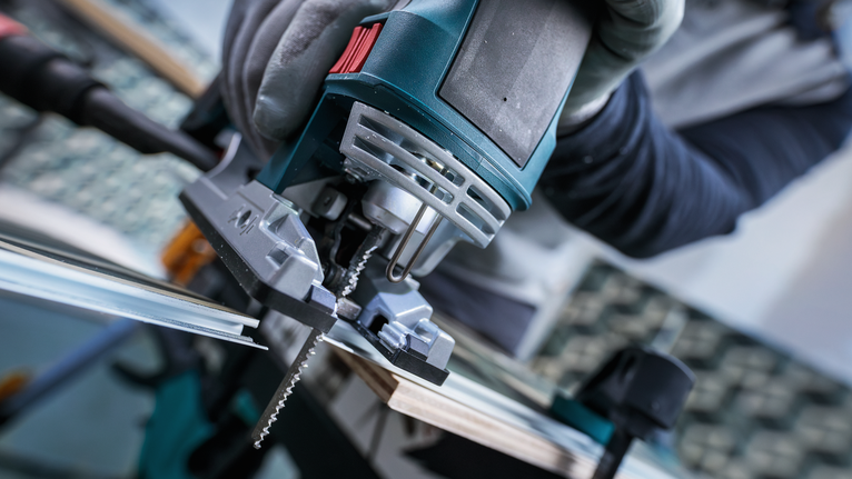 配戴安全設備的人員用曲線鋸切割木材。