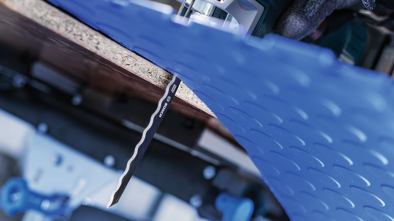PRO Soft Material T313AW 線鋸片,152 mm,3 件 一名佩戴安全設備的人使用曲線鋸切割藍色塑膠片。