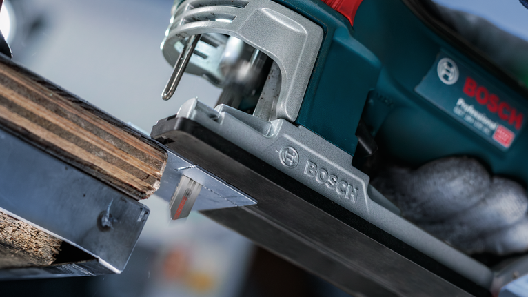 一名佩戴安全設備的人使用電動曲線鋸切割木材。