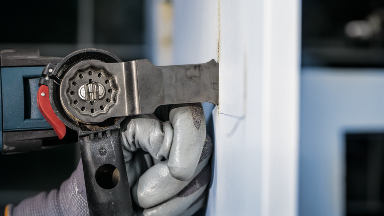 配戴安全設備的人員使用電動工具切割牆壁。