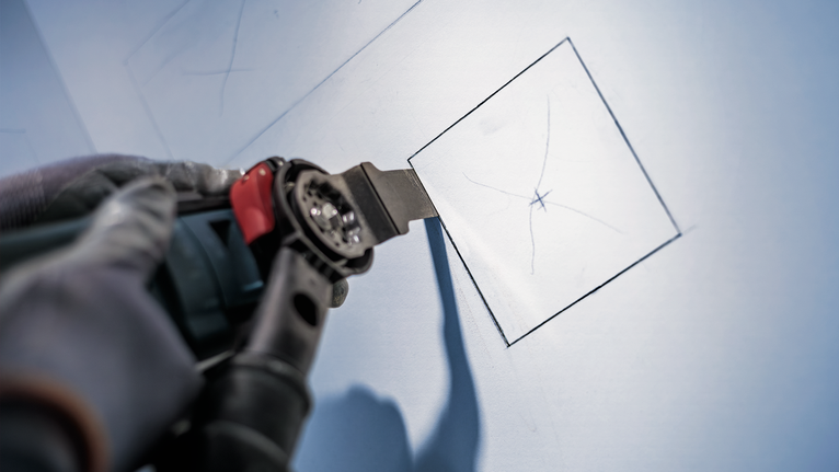 配戴安全設備的人員使用電動工具在幹牆上切割出一個正方形。