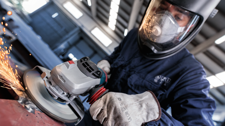 配戴安全設備的人研磨金屬，火花飛濺。