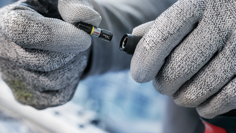 配戴安全設備的人員將螺絲起子頭放在鑽頭附件附近。