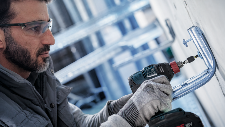 配戴安全設備的人員使用無線電鑽安裝金屬支架。