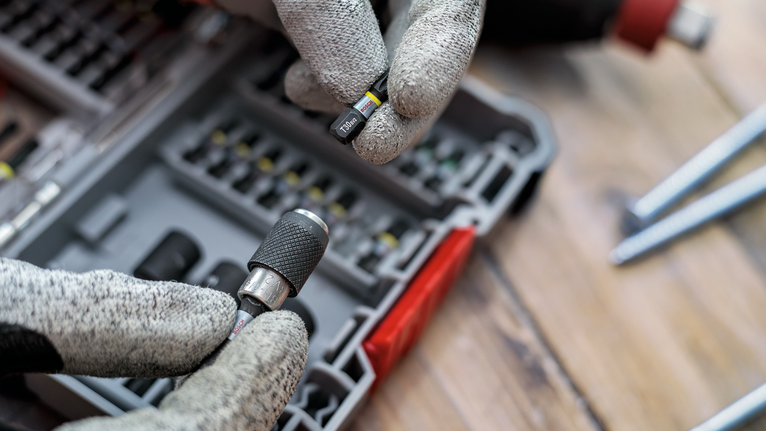 配戴安全設備的人員從有序的盒子中選擇一個螺絲起子頭。