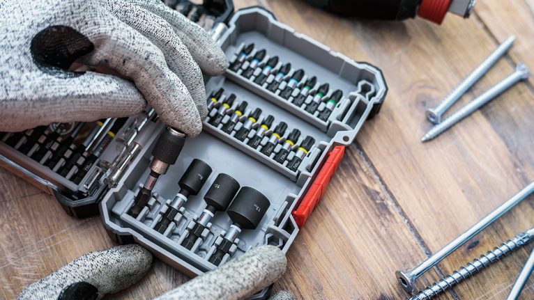 配戴安全設備的人員從有序的盒子中選擇一個螺絲起子頭。