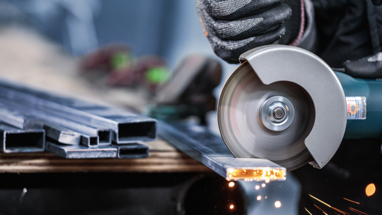 配戴安全設備的人用角磨機切割金屬，產生火花。