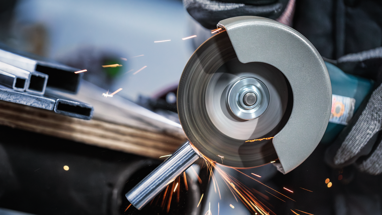 配戴安全設備的人員使用角磨機切割金屬管路。