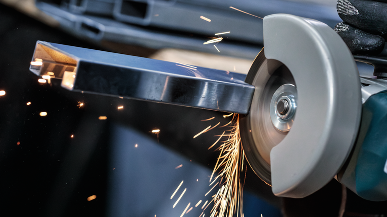 配戴安全設備的人研磨金屬，產生明亮的火花。