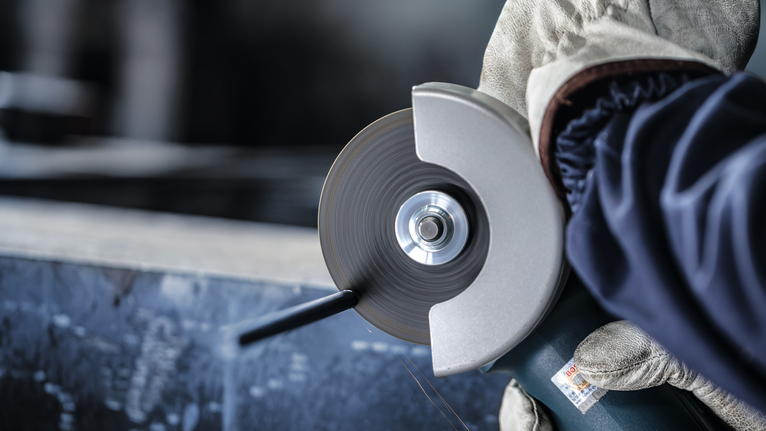 配戴安全設備的人員使用角磨機切割金屬。