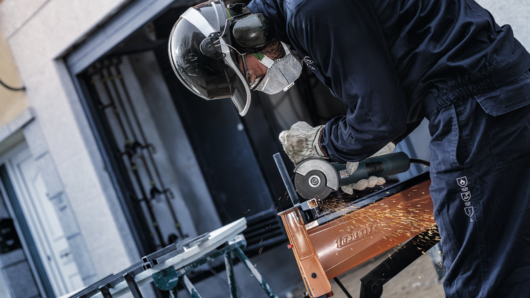 一名配戴安全設備的人正在研磨金屬，產生火花。