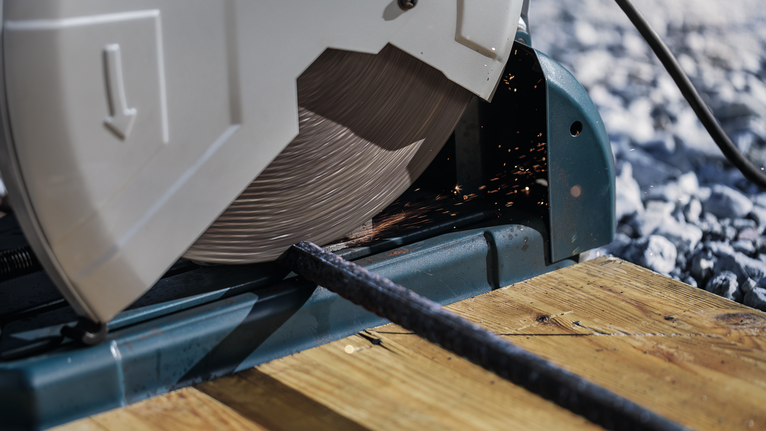 截鋸在木製平台上切割金屬棒。