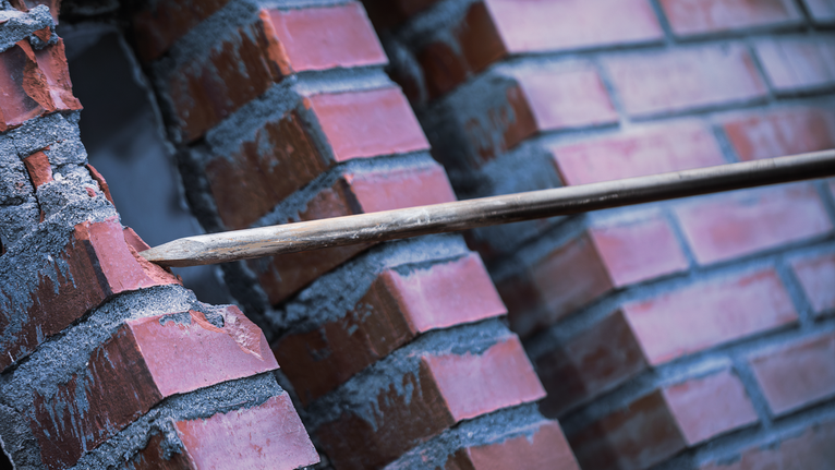 尖頭鑿子鑿穿磚牆。