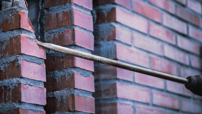 用鑽頭在磚牆上打一個洞。