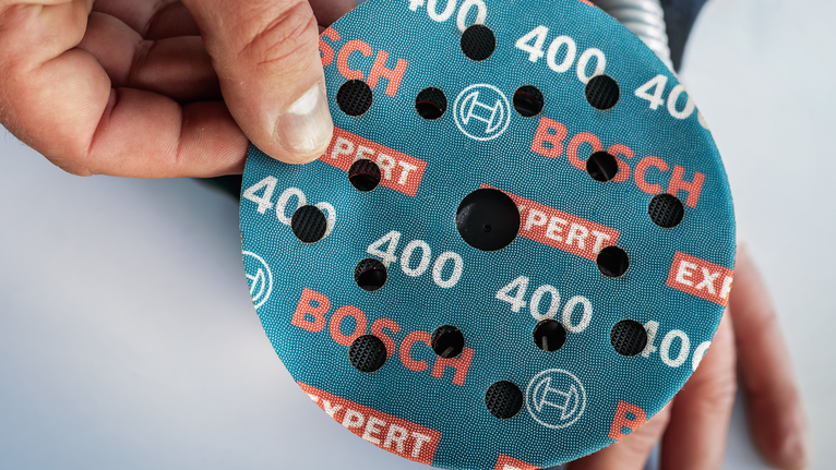 EXPERT O780 箔砂磨砂輪片,125 mm,G60 人員將圓形磨料砂輪放置在工具上。