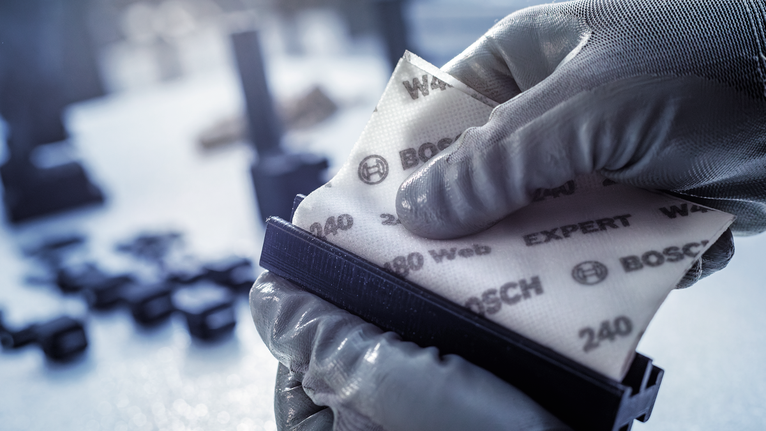 配戴安全設備的人員將砂紙固定在砂磨塊上。