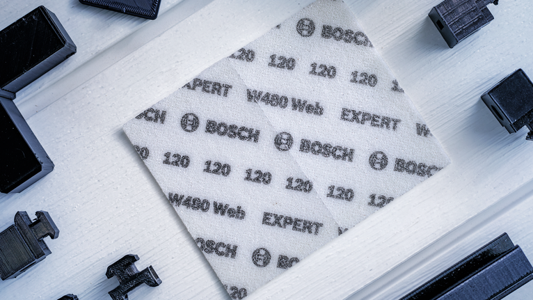 將印有規格的白色磨砂紙放置在淺色木質表面上。