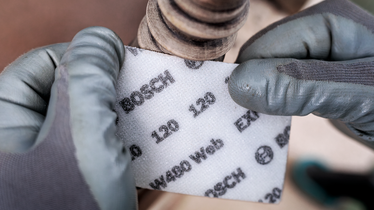 配戴安全設備的人員將磨料砂磨墊靠近金屬管。