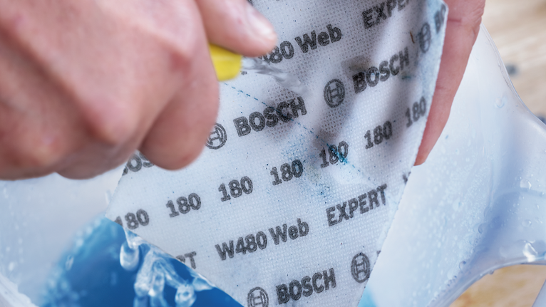 佩戴安全設備的人員將砂紙浸濕並擦洗在容器中。