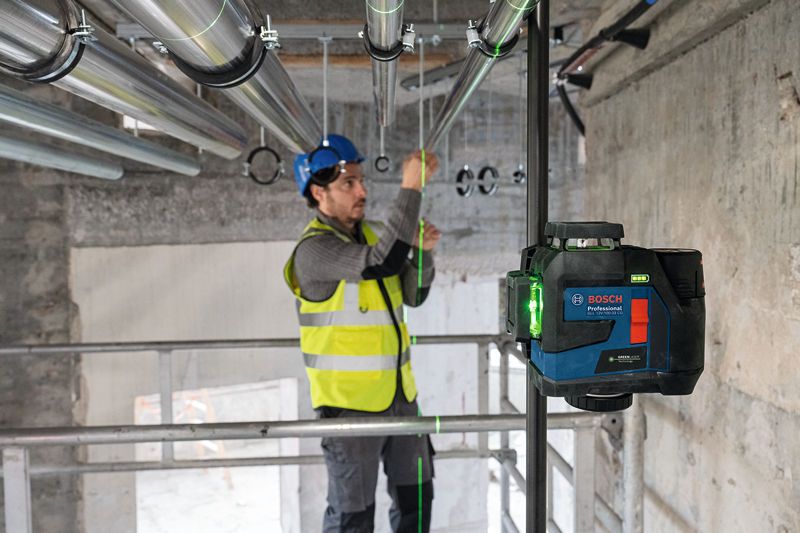 一名配戴安全設備的人員使用雷射調平工具對準管道。.