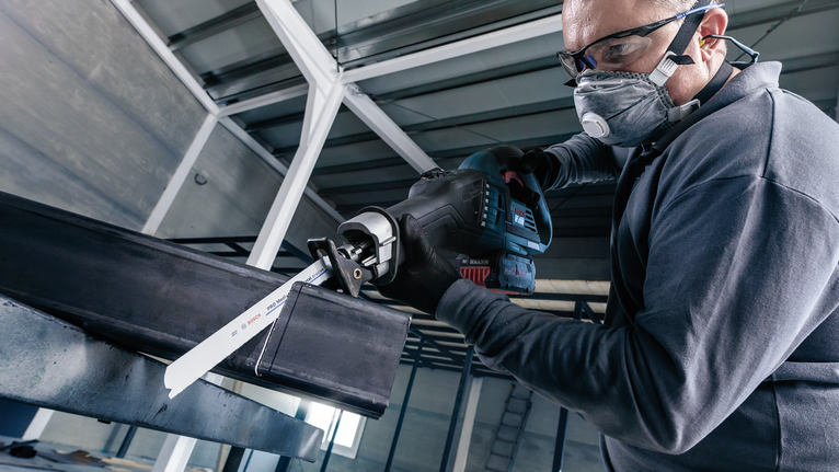 一名配戴安全設備的人員使用往復鋸切割金屬梁。