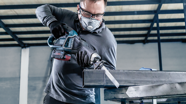 一名配戴安全設備的人員用往復鋸切割金屬梁。