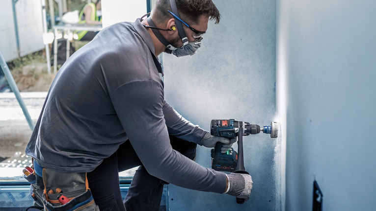 穿著安全設備的人在牆上鑽了一個大洞。