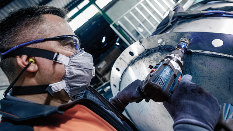 配戴安全設備的人員鑽入一個大型金屬圓筒。