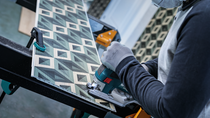 配戴安全設備的人員使用拼圖鋸切割圖案面板。