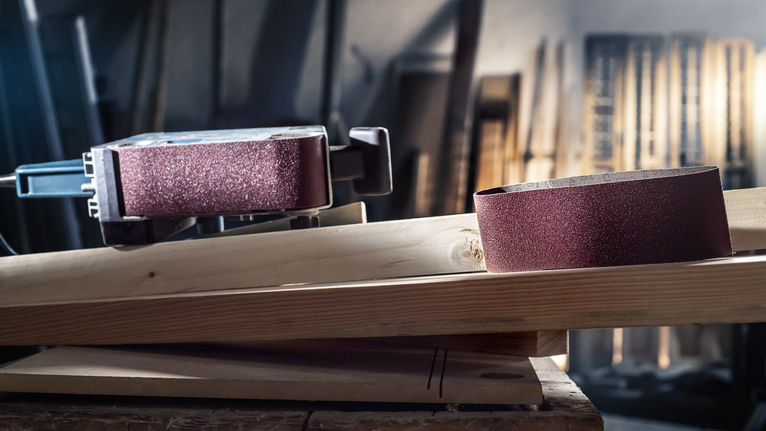 帶式砂光機和砂帶放置在車間的木板上。