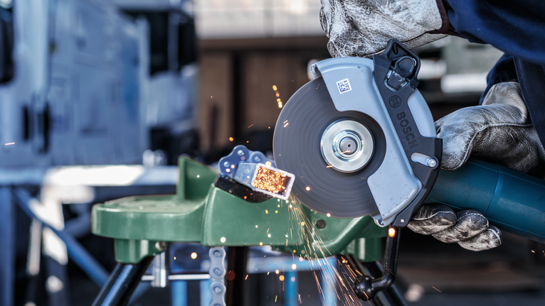 配戴安全設備的人用角磨機切割金屬管，火花飛濺。