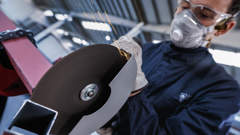 配戴安全設備的人員使用旋轉角磨機切割金屬。