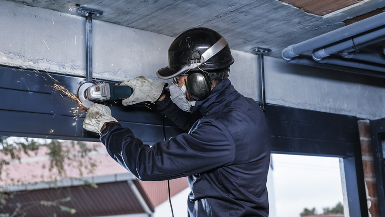 配戴安全設備的人研磨金屬梁，產生火花。