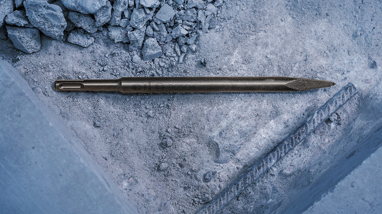 尖頭鑿子位於金屬鋼筋附近的混凝土碎石上。