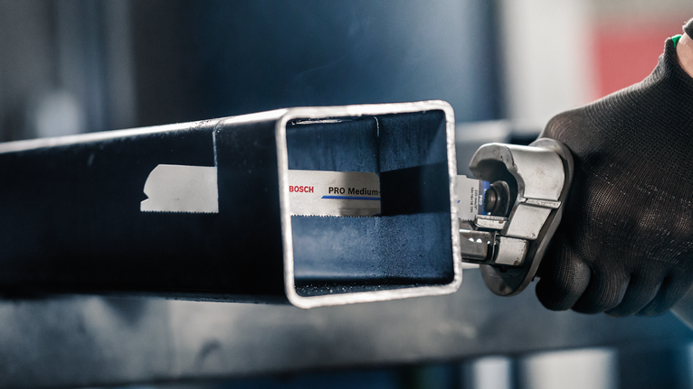 配戴安全設備的人員使用往復鋸切割金屬方管。