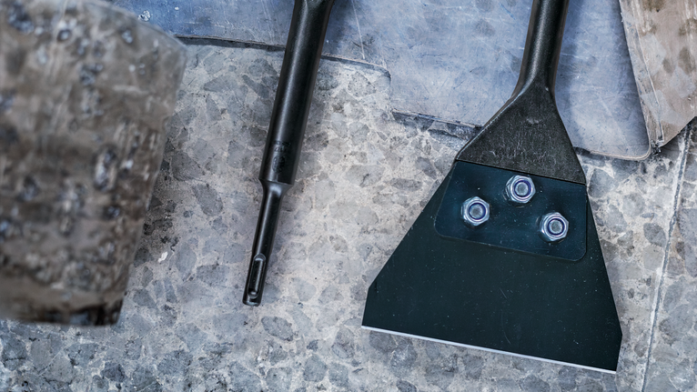 鑿子配件和工具放在石頭地板上，旁邊是一把磨損的木槌。