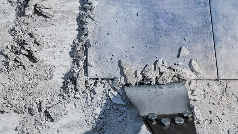 鑿子工具打碎了佈滿灰塵的地板上的瓷磚和碎片。