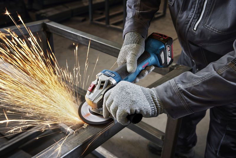 一名配戴安全設備的人員正在使用角磨機打磨金屬梁。.