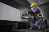 一名佩戴安全設備的人員在建築工地上打磨金屬。